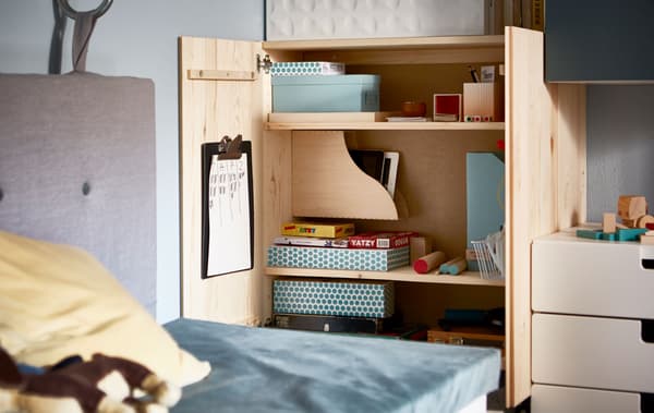 An open IVAR cabinet that’s organized with games in boxes and magazine files.