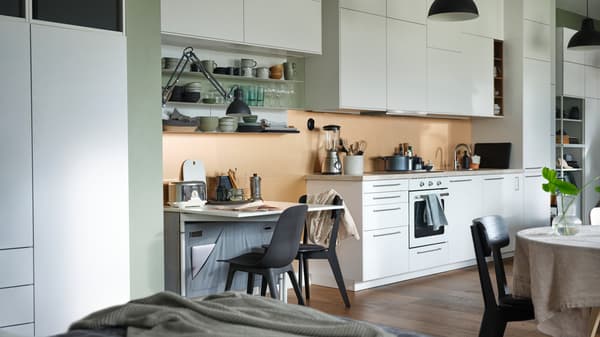 An open plan apartment with a KALLHÄLL gateleg table with storage and a white METOD kitchen with floor to ceiling cabinets.