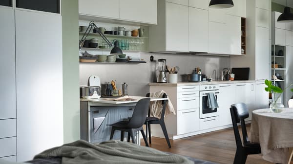 An open plan apartment with a KALLHÄLL gateleg table with storage and a white METOD kitchen with floor to ceiling cabinets.