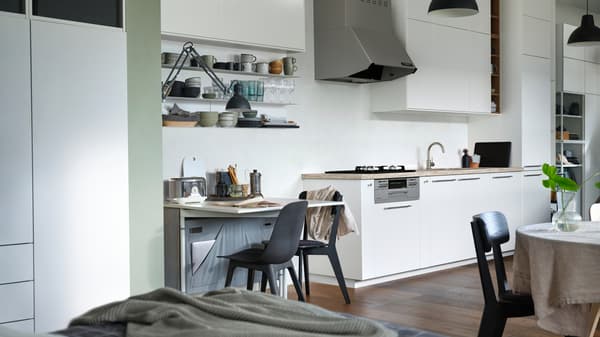 An open plan apartment with a KALLHÄLL gateleg table with storage and a white METOD kitchen with floor to ceiling cabinets.
