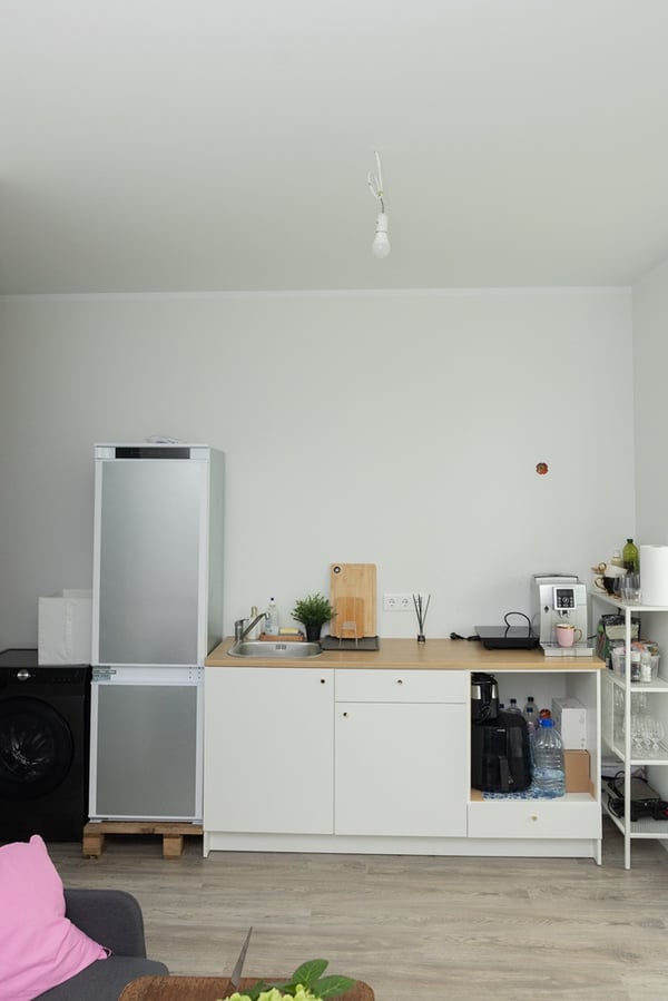 An open-plan kitchen with fitted units, a dining table, and chairs in a bright space.