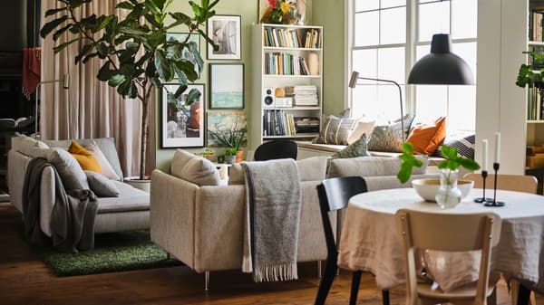 An open plan living and dining area with two beige/brown SÖDERHAMN 3-seat sofas, white BILLY bookcases and a gallery wall.