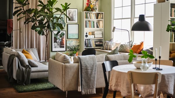 An open plan living and dining area with two beige/brown SÖDERHAMN 3-seat sofas, white BILLY bookcases and a gallery wall.