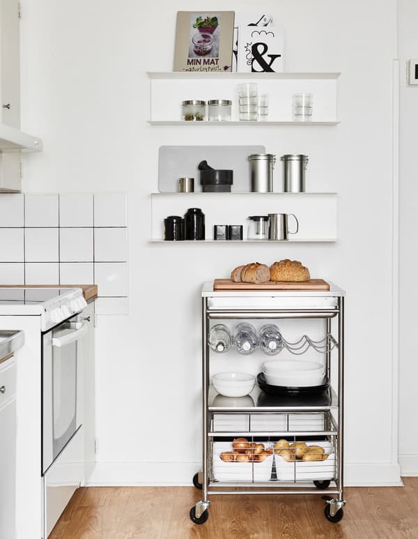 An open wall cabinet to keep cookbooks and food containers with a stainless steel trolley underneath provides flexible space.