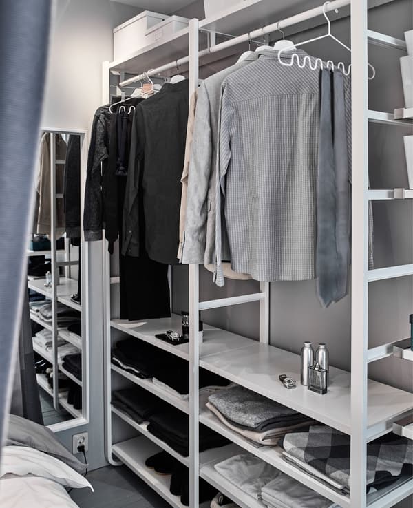 An open wardrobe share a small space with a sleeping space.