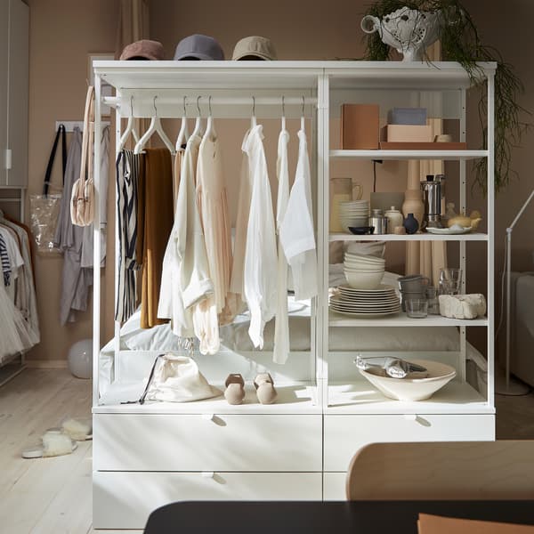An open wardrobe with drawers, shelves and a rail. Clothes hang on white hangers, and decorative items stand on the shelves.