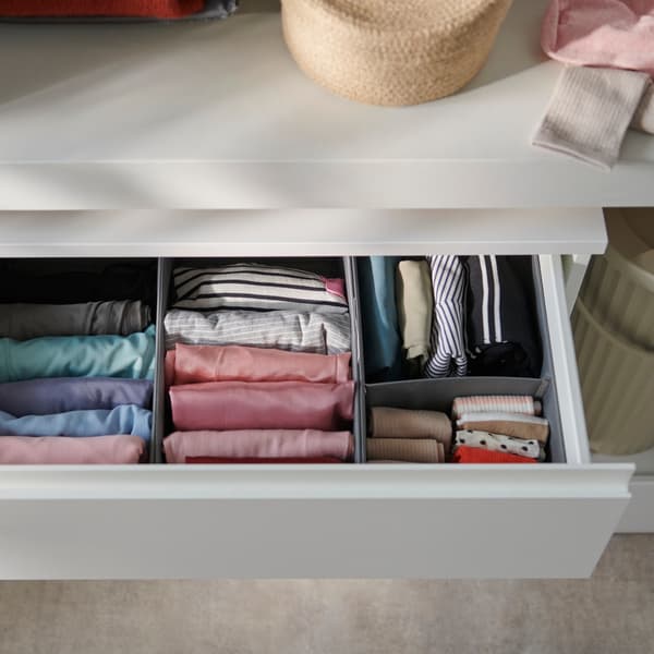 An open white chest of drawers revealing neatly folded clothing inside. 