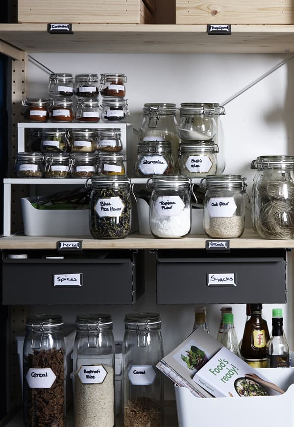 An open wooden shelf with glass jars in different sizes and different contents. 