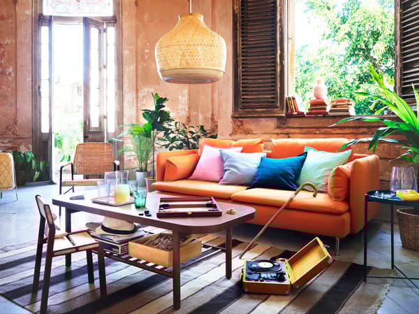 An orange sofa with various cushions, placed behind a dark brown coffee table.