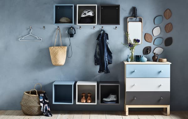 An organised hallway with hooks, different-coloured open IKEA EKET cabinets and a TARVA chest of drawers.