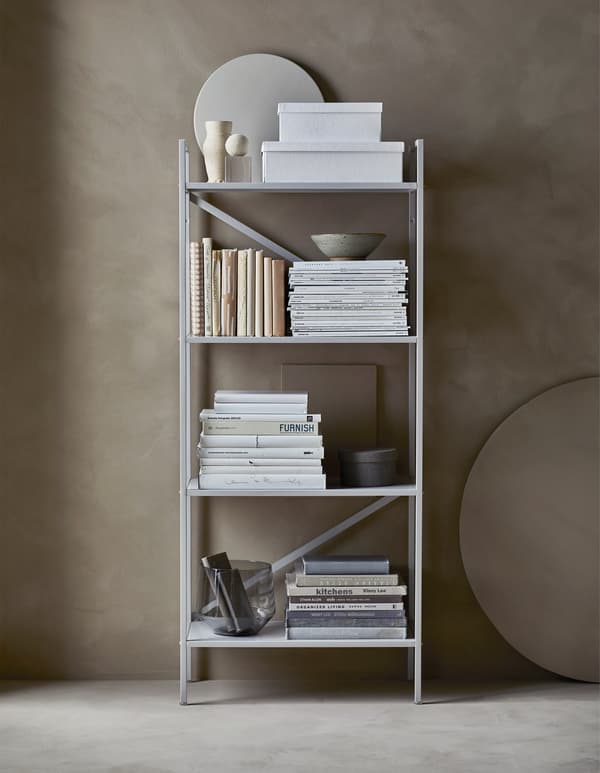 An organised, open shelving unit that holds storage boxes, books, magazines and decorative objects.