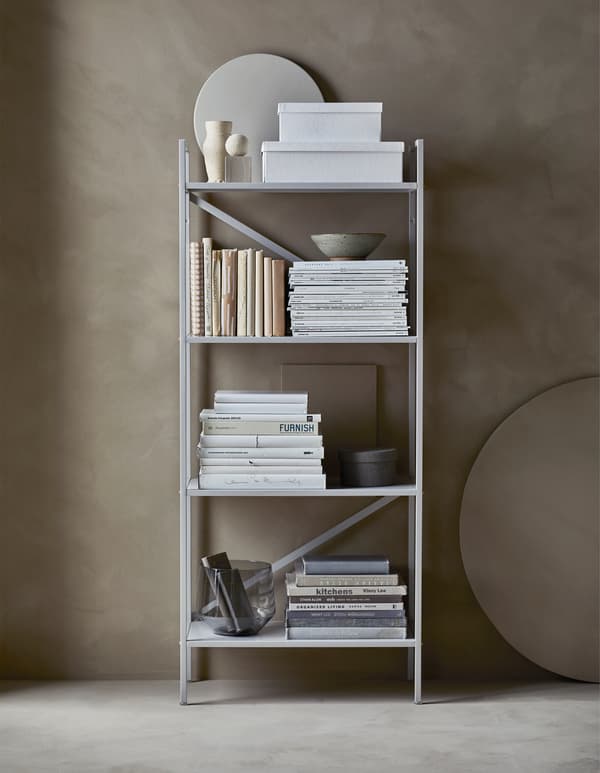 An organised, open shelving unit with storage boxes and books sorted by colours and covered in paper  