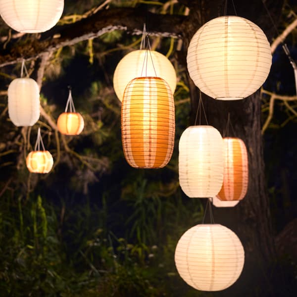 An outdoor area is illuminated by many white and striped orange SOLVINDEN pendant lamps that enhances the ambiance.