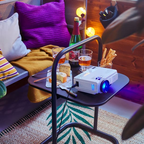 An outdoor bench with drinks and a projector set up on a small table.