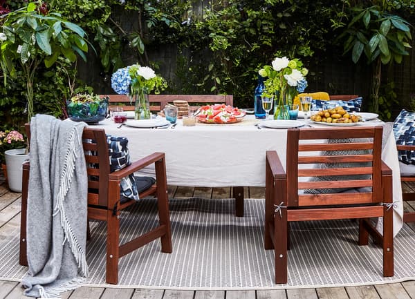 An outdoor dining table and chairs with a striped rug underneath.
