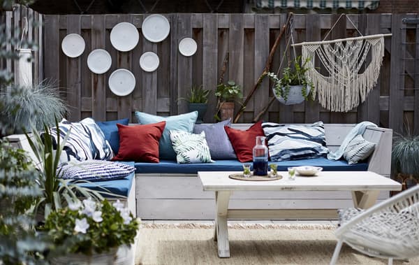 An outdoor living space with cushions and hanging plants.