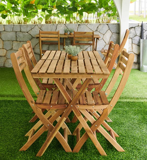 An outdoor setting with foldable tables and chairs placed on top of artificial grass.
