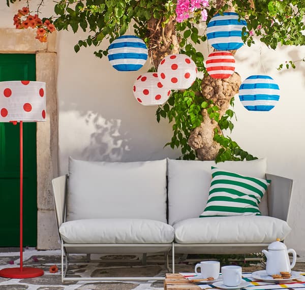 An outdoor sofa with decorative lighting hanging above it.