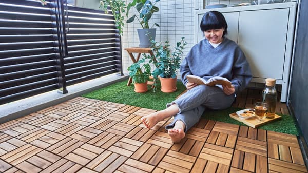 An outdoor space where RUNNEN floor decking in artificial grass and wood form different zones for eating and relaxing.