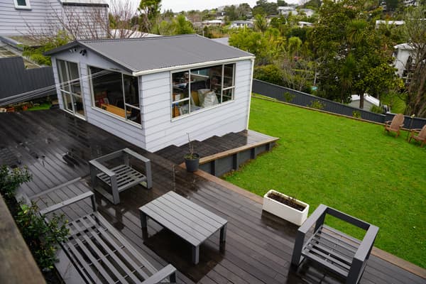 An outdoor space with a granny flat, outdoor furniture and lawn.