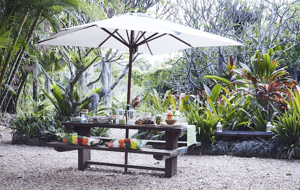 An outdoor table and bench with parasol.