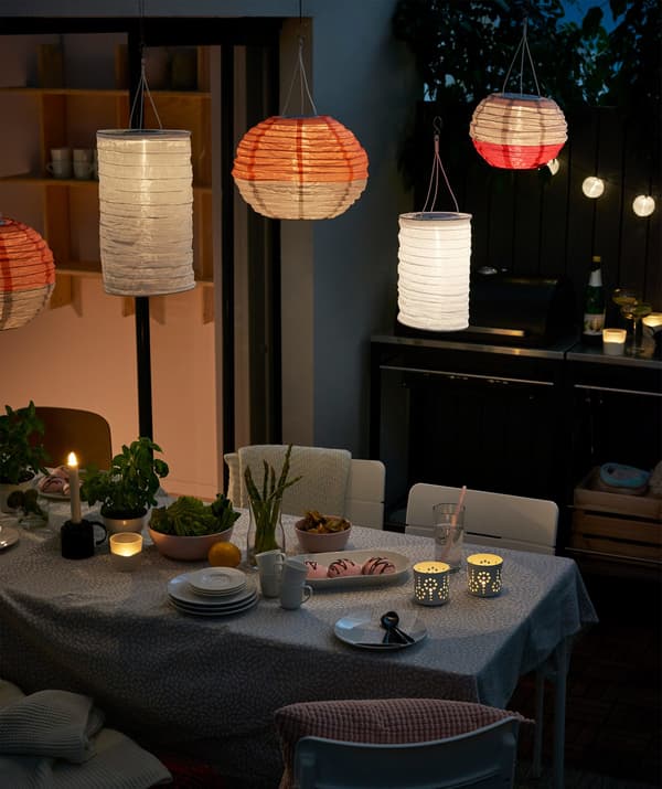 An outside dining area illuminated with IKEA SOLVINDEN solar-powered pendant lamps.