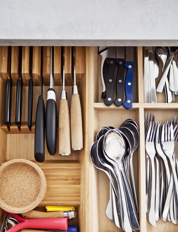 An overhead view of a drawer insert that's organised lots of knives and cutlery.