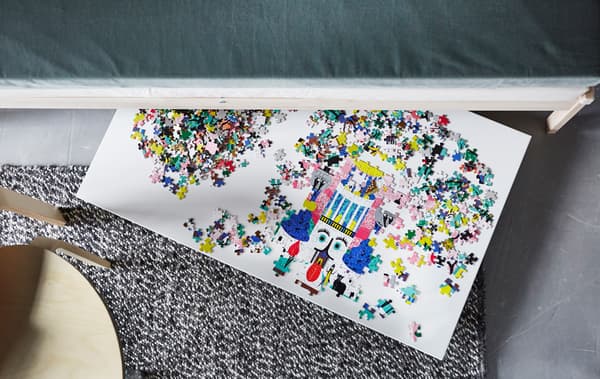 An overhead view of a puzzle on a board that’s sticking out from under a sofa