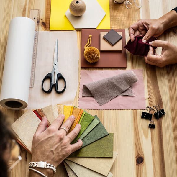 An overhead view of a wood table with many fabric swatches, paint swatches and different materials as part of an IKEA Family workshop.