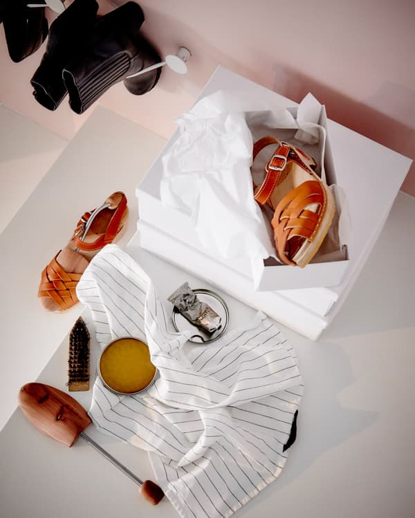 An overhead view of an open shoe box and leather sandles.