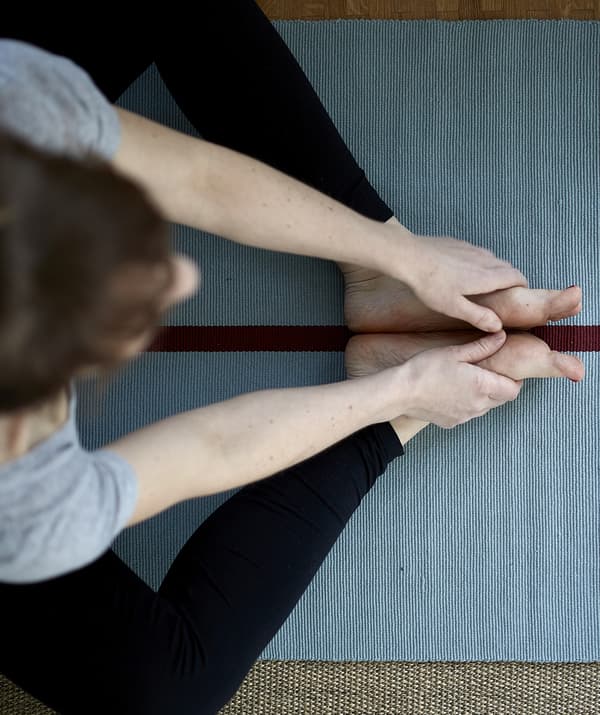 An overhead view of Eva practising yoga on a blue mat.