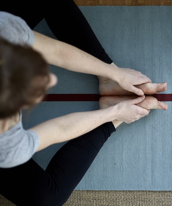 An overhead view of Eva practising yoga on a blue mat.