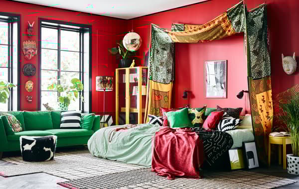 An overview of Cecilia's bold dream bedroom with bright African patterned textiles, colourful green furniture and red walls.