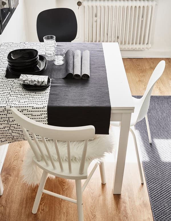 An updated white kitchen table combining different styles of white chairs and a dotted tablecloth.