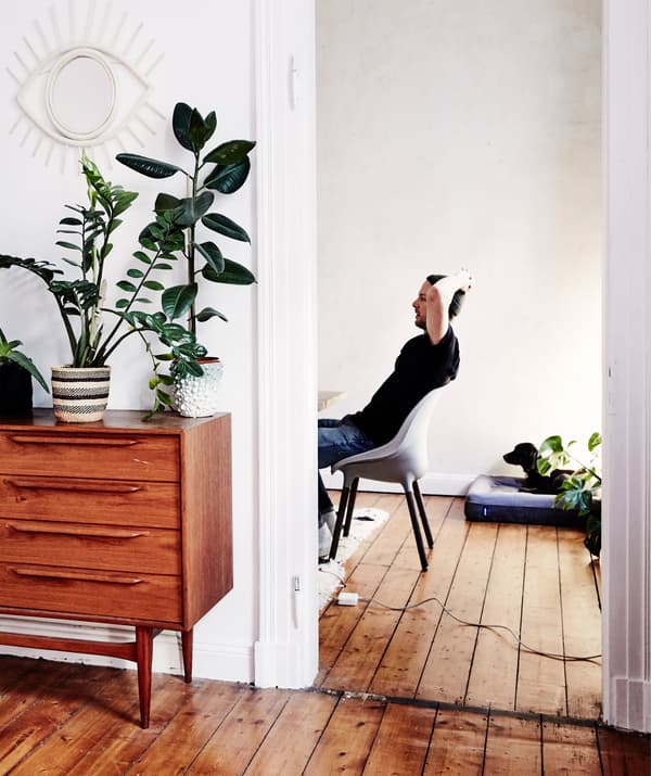 André assis sur une chaise, derrière une porte, avec du plancher en bois et du mobilier vintage.