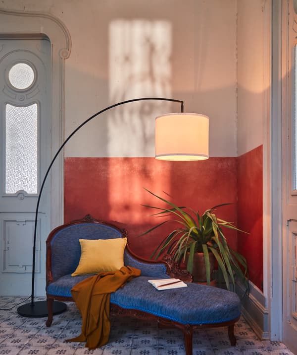 Angolo di una stanza decorato con materiali e dettagli raffinati. Lampada da terra SKAFTET ad arco sopra a una pianta e a una elegante chaise longue.