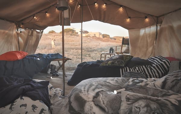 Animal-print bedding on beds under a canvas in the desert.