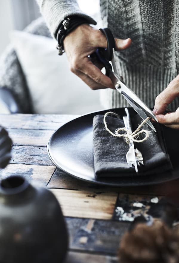 Anita tying cutlery and napkins with string.