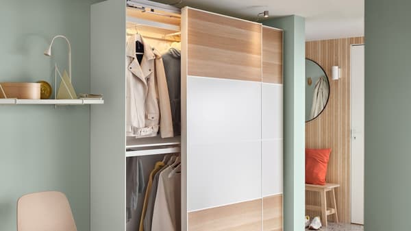 Ankleidezimmer mit weißem, offenem Kleiderschrank & Sessel.