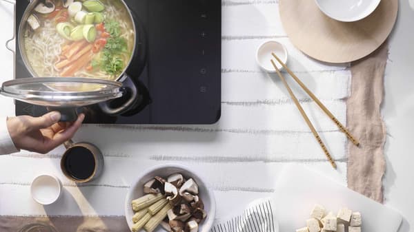 ANNONS pot with lid cooking noodles with vegetables on an induction cooker.