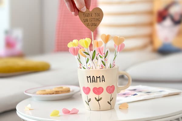 Ansicht der liebevolle handbemalten Tasse für den Muttertag mit einem Gruß aus Papierblumen zum Rausziehen. 