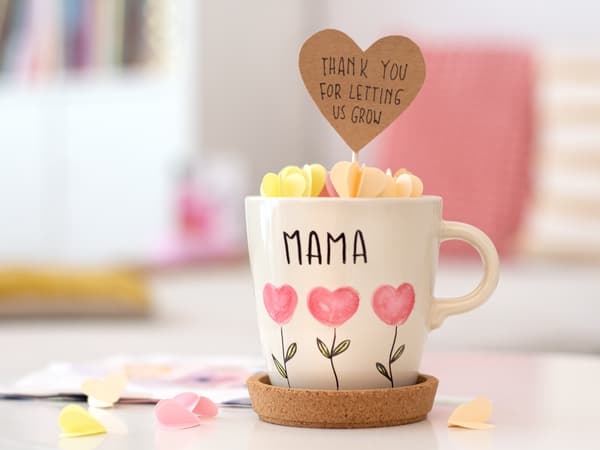 Ansicht der liebevolle handbemalten Tasse für den Muttertag mit einem Gruß aus Papierblumen zum Rausziehen. 