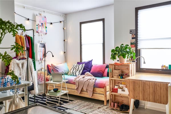 Apartamento pequeno moi ben equipado con estante, colgadoiro e un sofá realizado con coxíns e dúas camas baixas unha sobre outra.