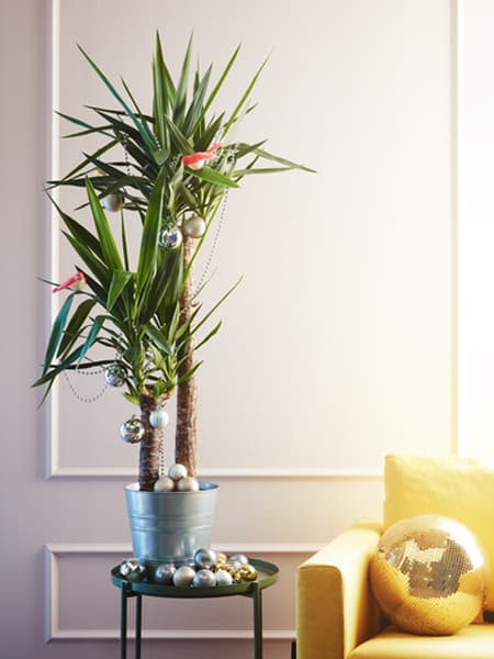 Árbol de Navidad moderno con una planta de interior con maceta metálica decorada con motivos navideños 