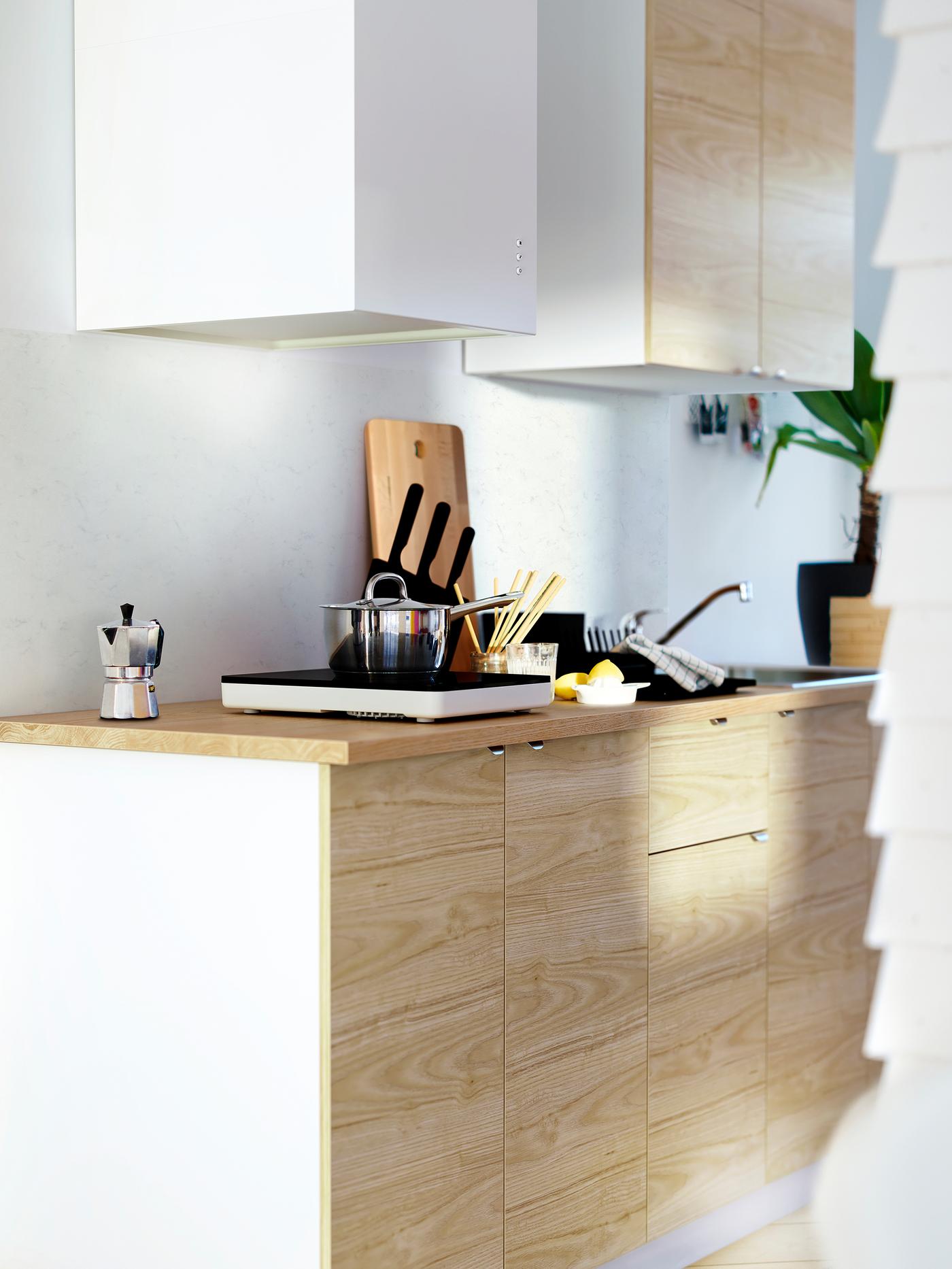 Armaris METOD d'IKEA amb frontals de fusta llista i efecte freixe, i un taulell de fusta amb una placa portàtil.