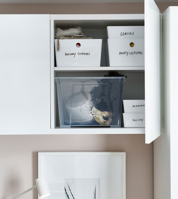 Armoire au-dessus du lit, ouverte, avec des boîtes étiquetées à l’intérieur.