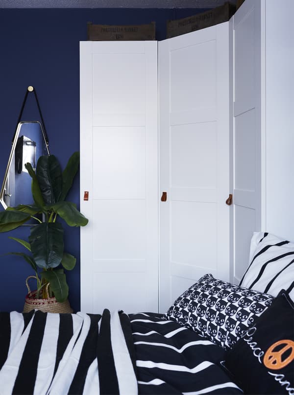 Armoire d'angle blanche dans une chambre bleue.