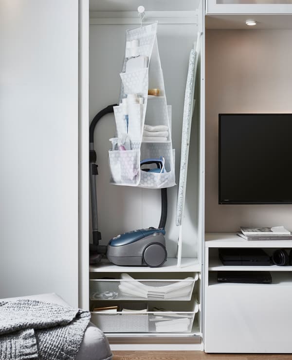 Armoire destinée au matériel de nettoyage et d’entretien du linge, avec aspirateur, fer et planche à repasser.