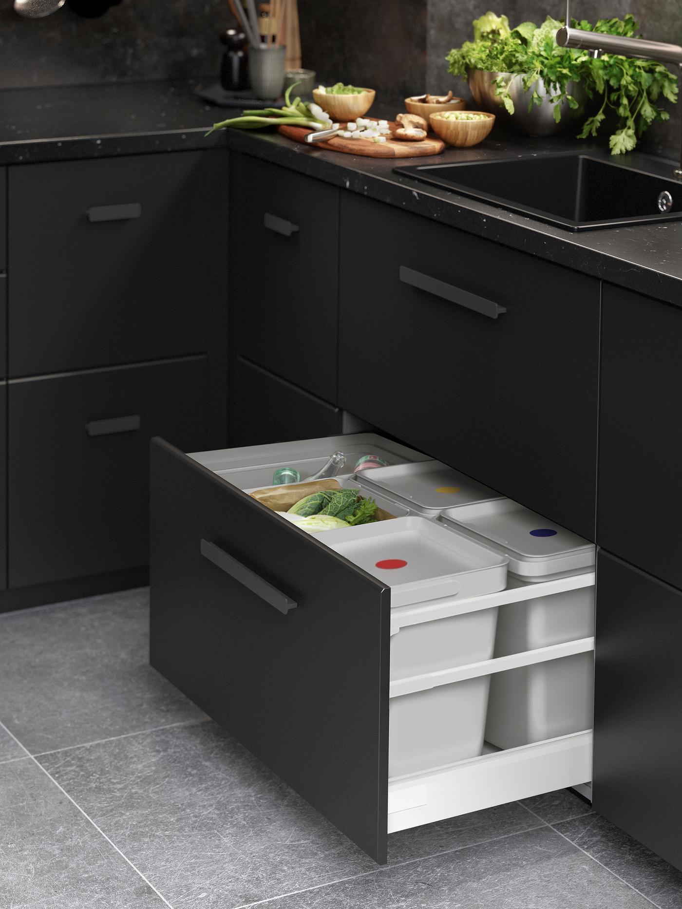 Armoires avec façades de tiroirs KUNGSBACKA anthracite. Un tiroir est ouvert et contient une poubelle HÅLLBAR gris clair.