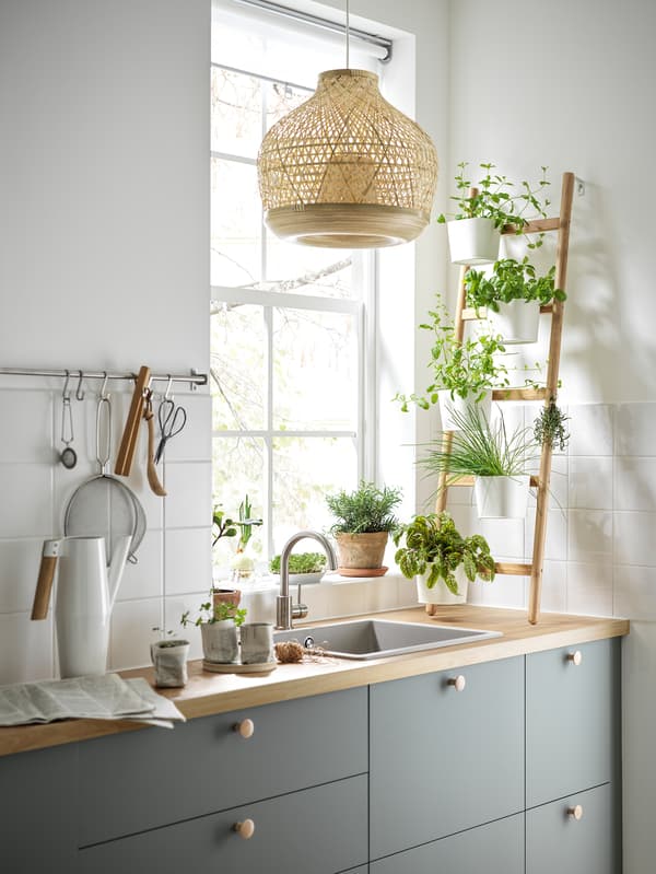 Armoires de cuisine avec des façades de tiroirs gris-vert, un comptoir en chêne plaqué, un évier en quartz gris-beige et un piédestal.